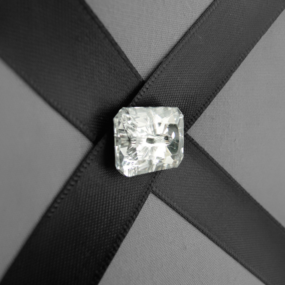 Close-up of silvery grey fabric, charcoal satin ribbons and diamante buttons